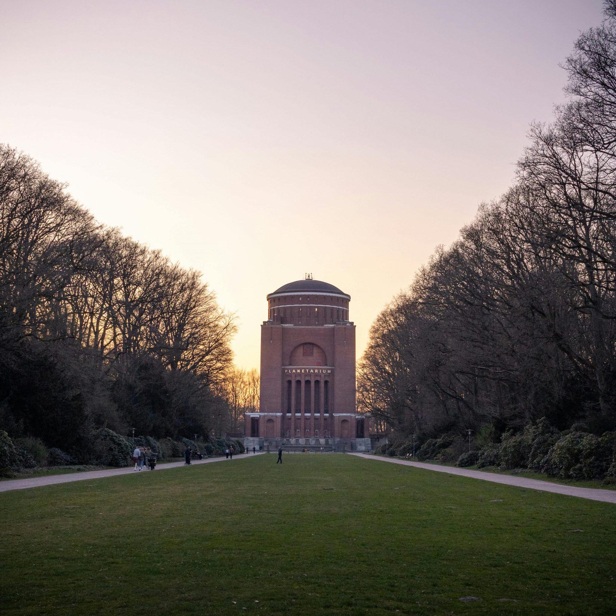Captivating sunset view of the iconic Hamburg Planetarium surrounded by trees.